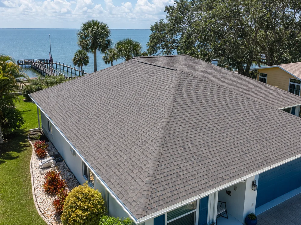 Completed shingle roof with straight ridge caps and clean drip edge lines on a Florida coastal home